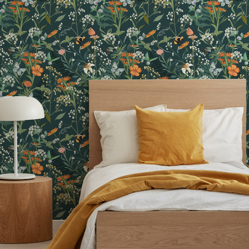 Bedroom with green floral meadow wallpaper with botanical elements and bees, wooden headboard, and yellow bedding.
